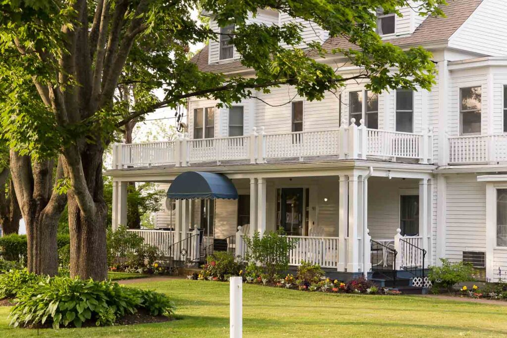 house in ogunquit maine with white columns and treed yard