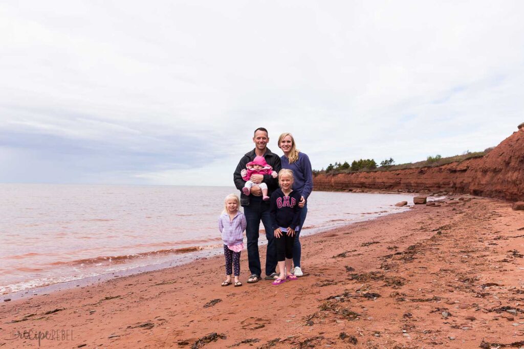 family photo on red sand beach in Prince Edward Island