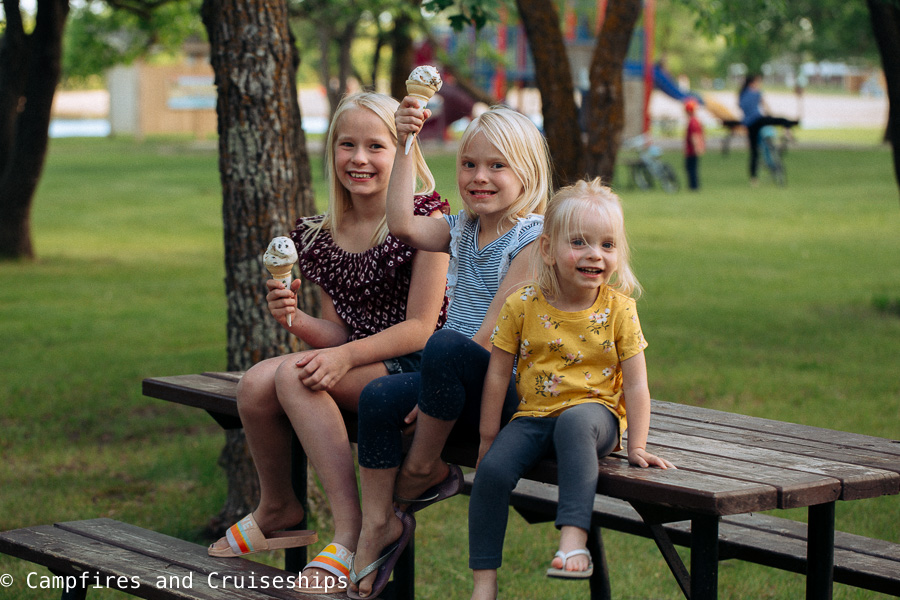 three girls eating ice cream sitting on a picnic table