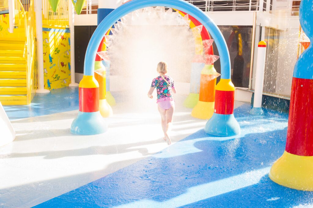 girl running through sprinkler on carnival horizon